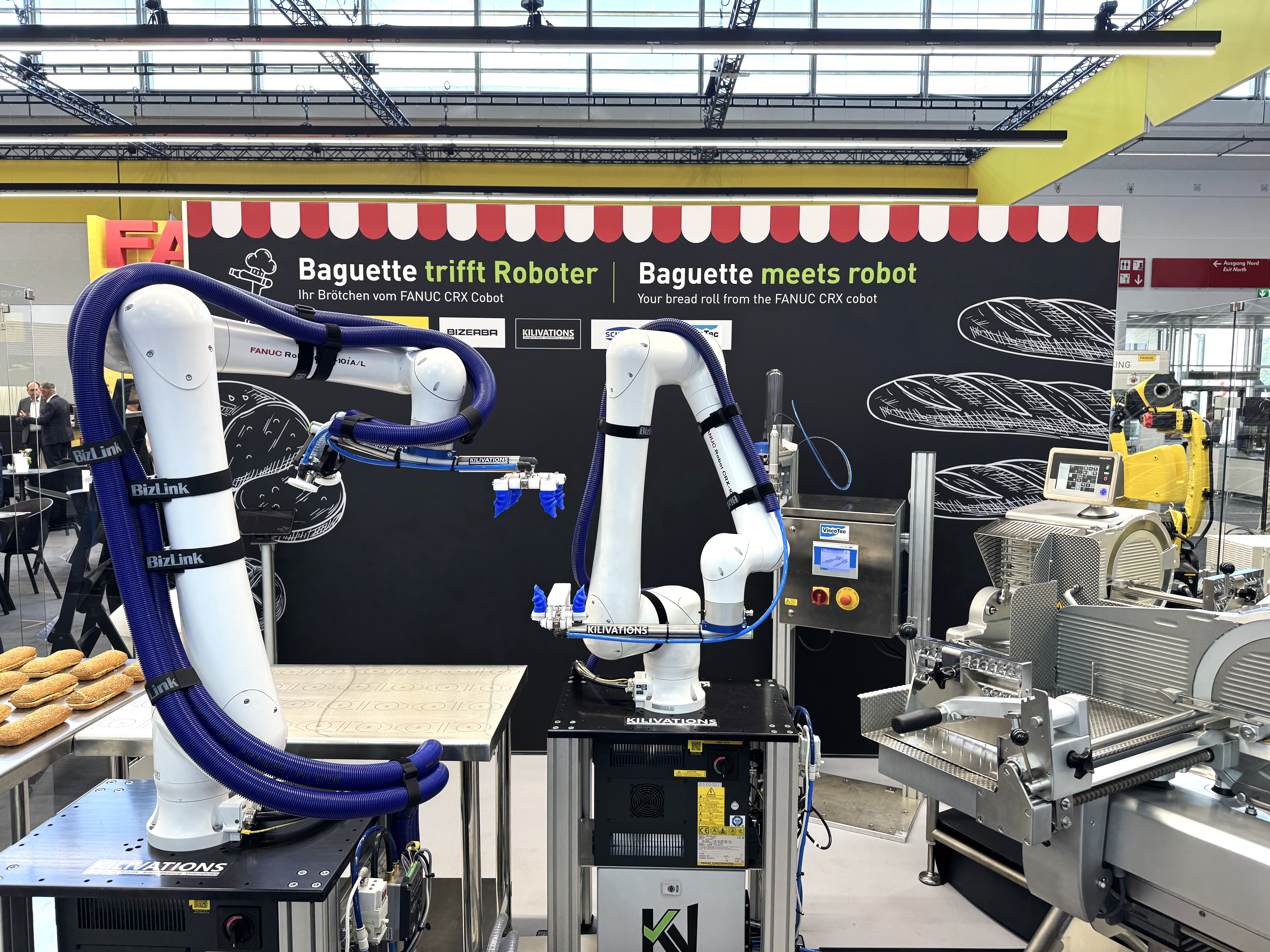 Ακρίβεια με τη βοήθεια ρομπότ στα καλύτερά της: Ο αυτοματοποιημένος σταθμός σάντουιτς συνδυάζει τον τεμαχισμό, τη δοσολογία και το χειρισμό σε μια απρόσκοπτη διαδικασία.